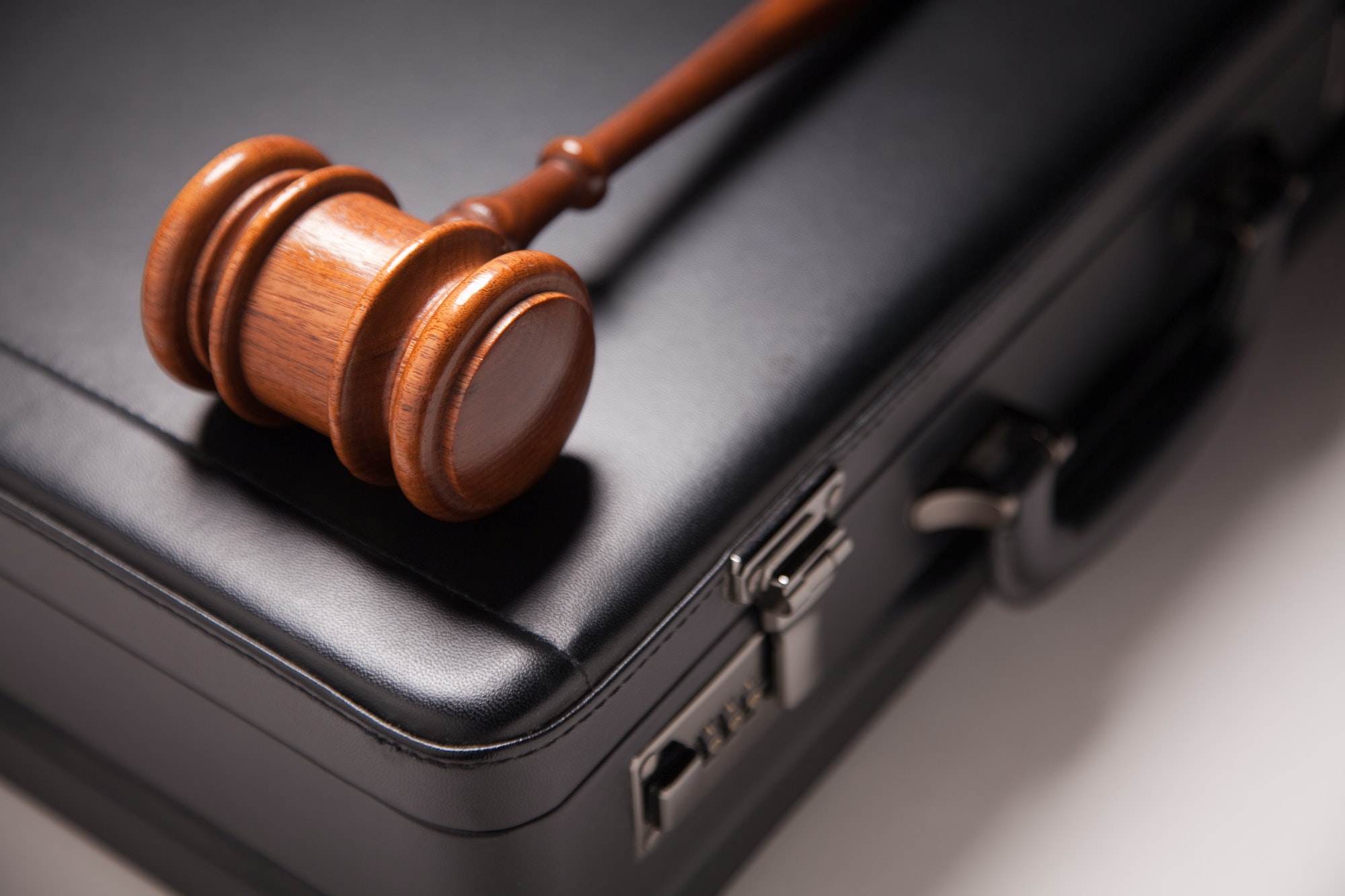 Gavel and Black Briefcase on Gradated Background with Selective Focus - Business Law Concept.